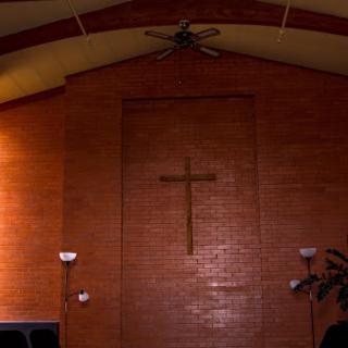 Interior view of a church featuring a wooden cross on a brick wall.