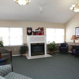 A cozy living room with a fireplace, seating area, and large windows.