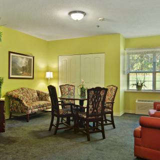 A cozy living room with yellow walls, featuring a dining table, sofa, and large window.