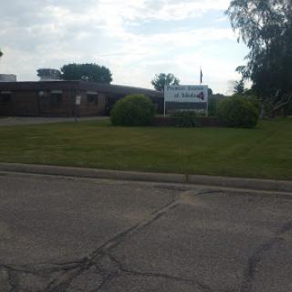 A view of a building with a sign in front, set against a cloudy sky and well-maintained grass.