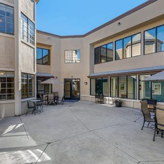 An open courtyard with outdoor seating surrounded by a building with large windows.