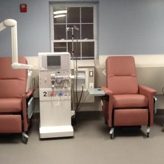 A dialysis station with two patient chairs in a hospital setting.