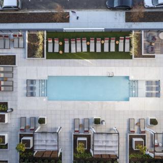 Aerial view of a modern rooftop swimming pool surrounded by lounging areas.