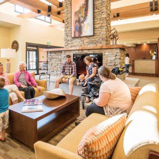 A group of people socializing in a cozy hotel lobby with comfortable seating and a central fireplace.