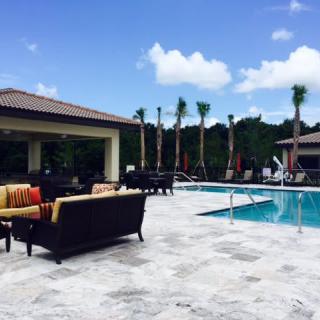 A sunny poolside area with outdoor furniture and palm trees.