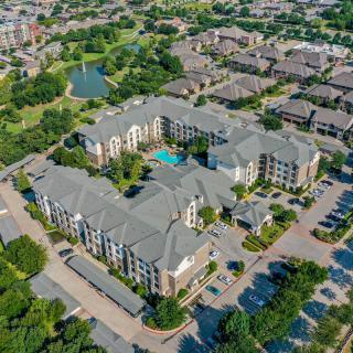 Aerial view of a large apartment complex with a central pool and surrounding parking lot in an urban neighborhood.