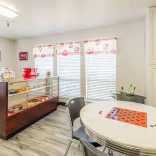 A bright and modern cafe interior featuring a dining area with a display case.