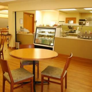 A cozy cafe interior with a round table and chairs, featuring a display case and counter in the background.