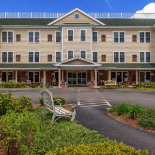 The exterior of a three-story building with landscaped gardens and a welcoming entrance.