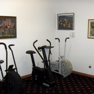 A room with stationary bikes and paintings on the wall.