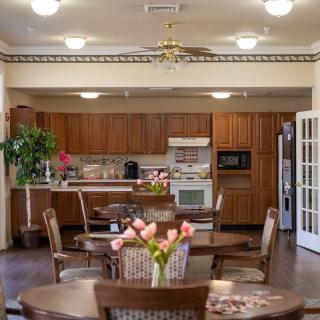A cozy kitchen and dining area with wooden cabinetry, a table with flowers, and modern appliances.