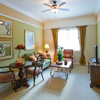 A cozy living room with elegant decor and furniture, featuring a sofa, chairs, coffee table, and wall art.