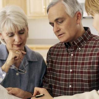 An older couple engaged in a discussion at the kitchen table.