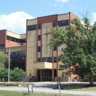 A modern school building surrounded by trees on a sunny day.