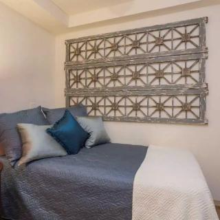 A cozy bedroom with decorative wall art and neatly arranged pillows on the bed.