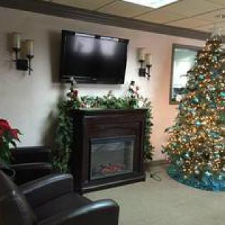A cozy living room decorated for the holidays with a Christmas tree, fireplace, and comfortable seating.