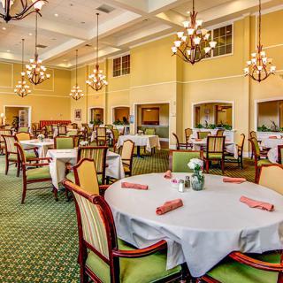 An elegant dining room with neatly arranged tables and chairs, adorned with chandeliers.