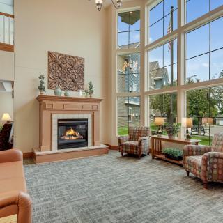 A spacious and modern living room with a fireplace and large windows, featuring comfortable seating and elegant decor.