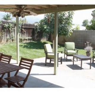 A cozy backyard patio with seating and a lush green lawn.