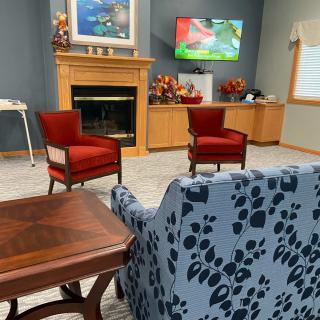 A cozy living room with a fireplace, adorned with red chairs and stylish furniture.