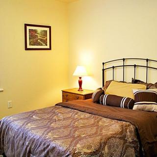 A cozy bedroom with a neatly made bed, a bedside table, and a lamp providing warm lighting.