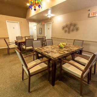 A well-furnished dining area with a large table and several chairs, featuring warm lighting and tasteful decor.