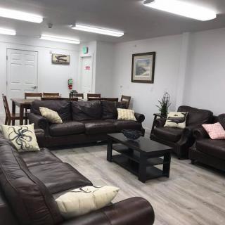 A modern living room and dining area featuring brown leather sofas, a black coffee table, and a dining table with chairs.