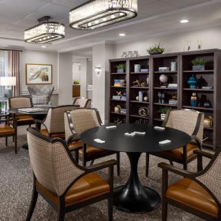 A modern living room featuring comfortable seating, a central table, and bookshelves filled with decorative items.