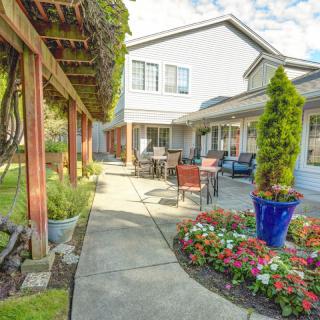 A beautiful garden patio with outdoor seating and vibrant plants surrounding a modern building.