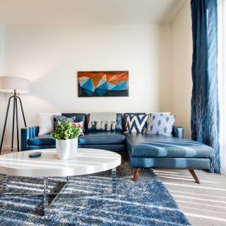 A modern living room with a blue sofa, abstract artwork, and a round coffee table.