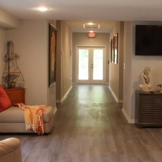 A modern living room with a hallway leading to double doors, featuring contemporary decor and wood flooring.