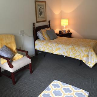 A cozy bedroom with a single bed and complementary yellow decor.