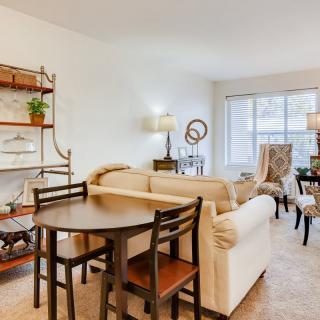 A cozy living and dining area with comfortable sofas, a table with chairs, a bookshelf, and decorative elements.