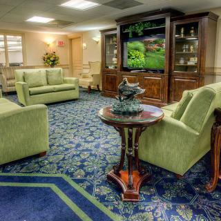 A cozy lobby seating area with green sofas and a television.