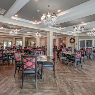 Elegant dining room with chandeliers and neatly arranged tables and chairs.