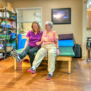 Two women share a joyful moment during a physical therapy session.