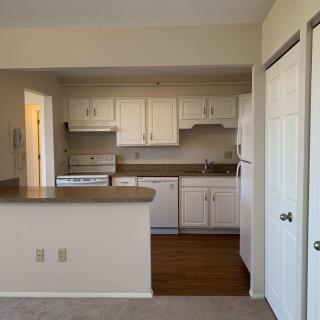 A compact apartment kitchen with white cabinets and standard appliances.