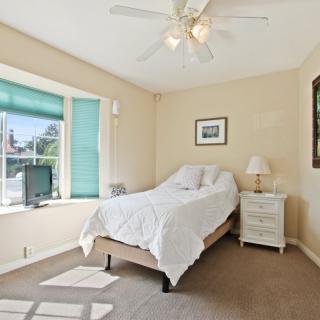A small bedroom with a bed, window, and dresser.