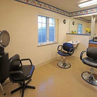 An interior view of a hair salon with styling chairs and a mirror.