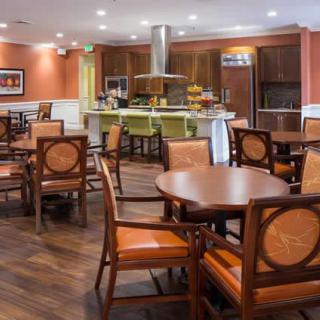 A cozy dining area with wooden tables and chairs, adjacent to an open kitchen.