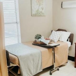A clean and well-organized hospital room featuring a single bed with an overbed table.