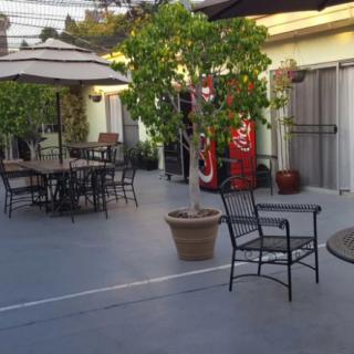 A quiet outdoor patio with tables, chairs, potted plants, and a vending machine in the evening.