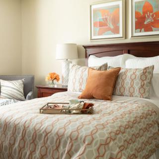 A cozy bedroom with a neatly arranged bed, stylish pillows, and warm decor.