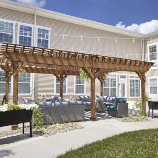 A tranquil outdoor patio with a wooden pergola and seating area.