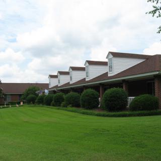 A row of residential buildings with manicured lawns under a cloudy sky.