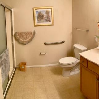 A well-lit bathroom featuring a toilet, sink, and shower with a framed picture on the wall.