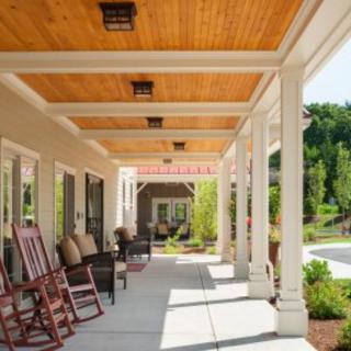A serene porch with wooden rocking chairs and elegant columns, overlooking a landscaped area.
