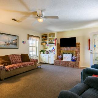 Cozy living room with a brick fireplace, featuring comfortable sofas, a television, and a ceiling fan.