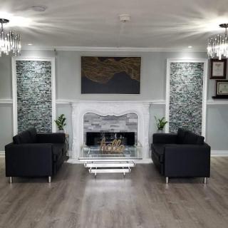 A modern living room with a fireplace, black chairs, and elegant chandeliers.