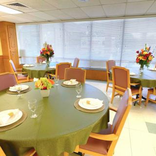 A well-set dining area with round tables, chairs, and floral centerpieces.